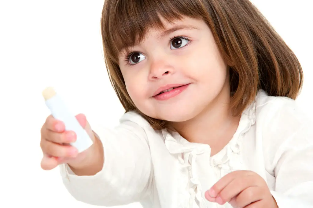 Portrait of little girl with lip balm.
